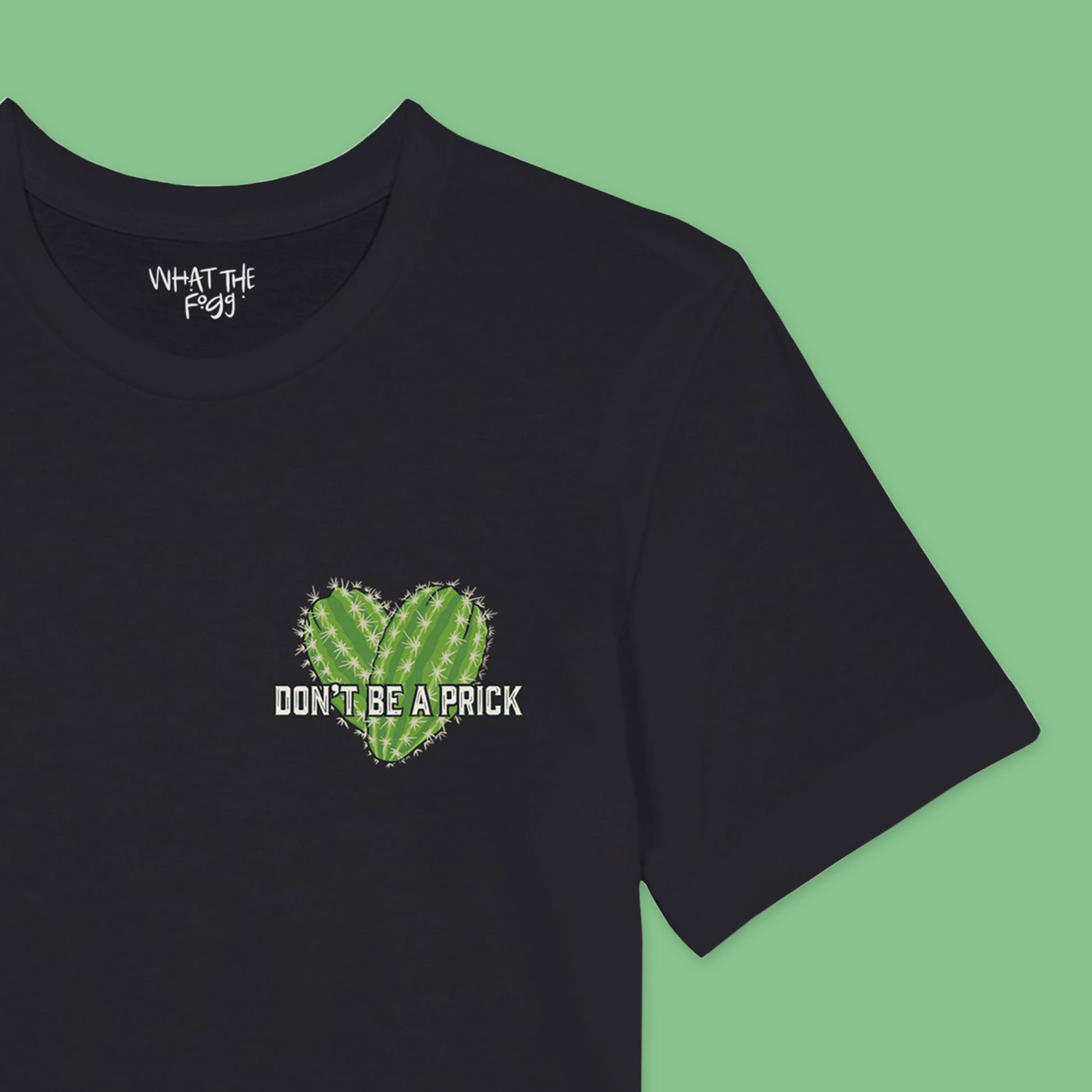 Close up of Black t-shirt featuring a chest badge with an illustration that reads 'Don't Be a Prick.' The design includes two cactuses arranged in the shape of a heart behind the text."