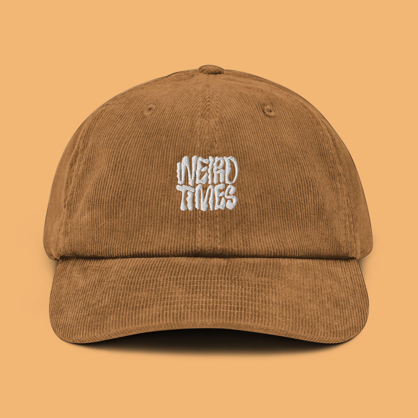 Front angle of a camel-coloured corduroy hat with 'Weird Times' printed in white on the front.