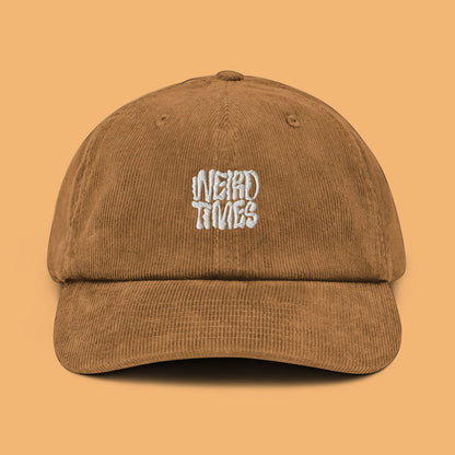 Front angle of a camel-coloured corduroy hat with 'Weird Times' printed in white on the front.