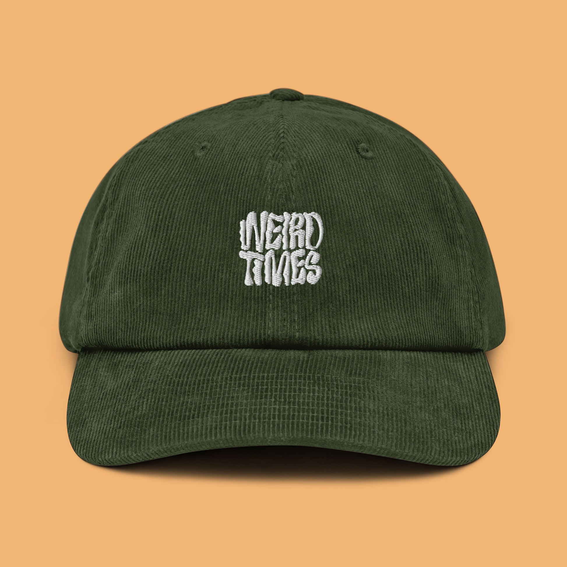 Front angle of a dark olive-coloured corduroy hat with 'Weird Times' printed in white on the front.
