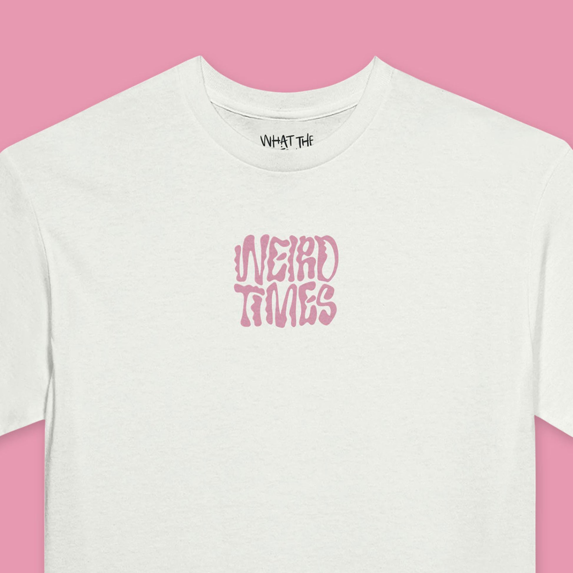 Close up of White T-shirt with 'Weird Times' printed in pink in the centre of the front.
